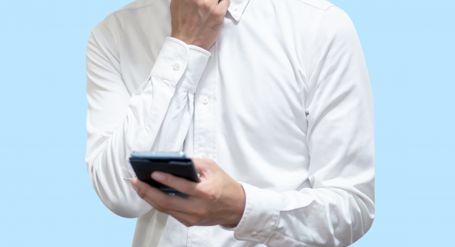スマートフォンを持って悩む男性